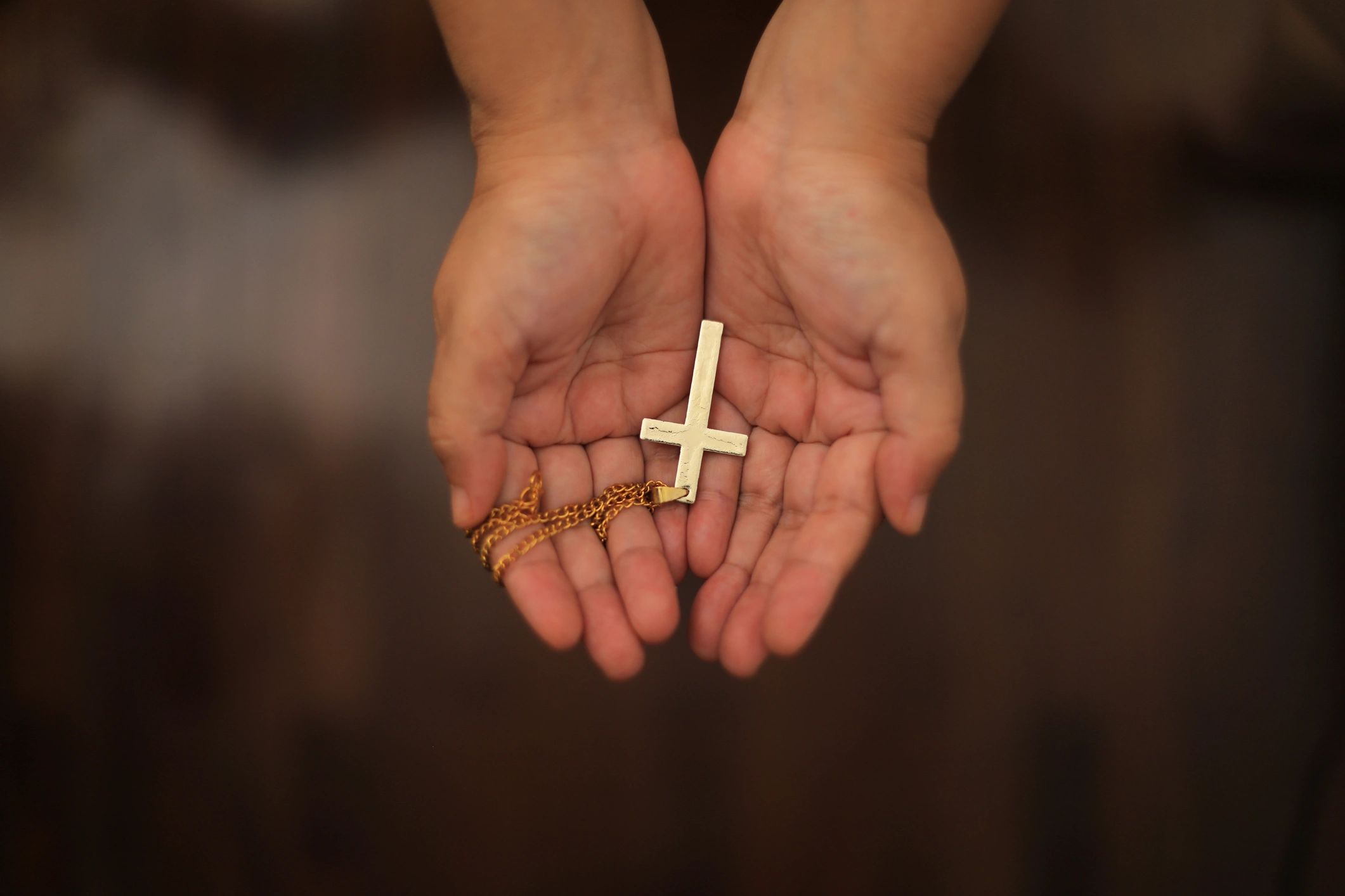 Mains tenant une croix, dans une atmosphère de silence et de prière