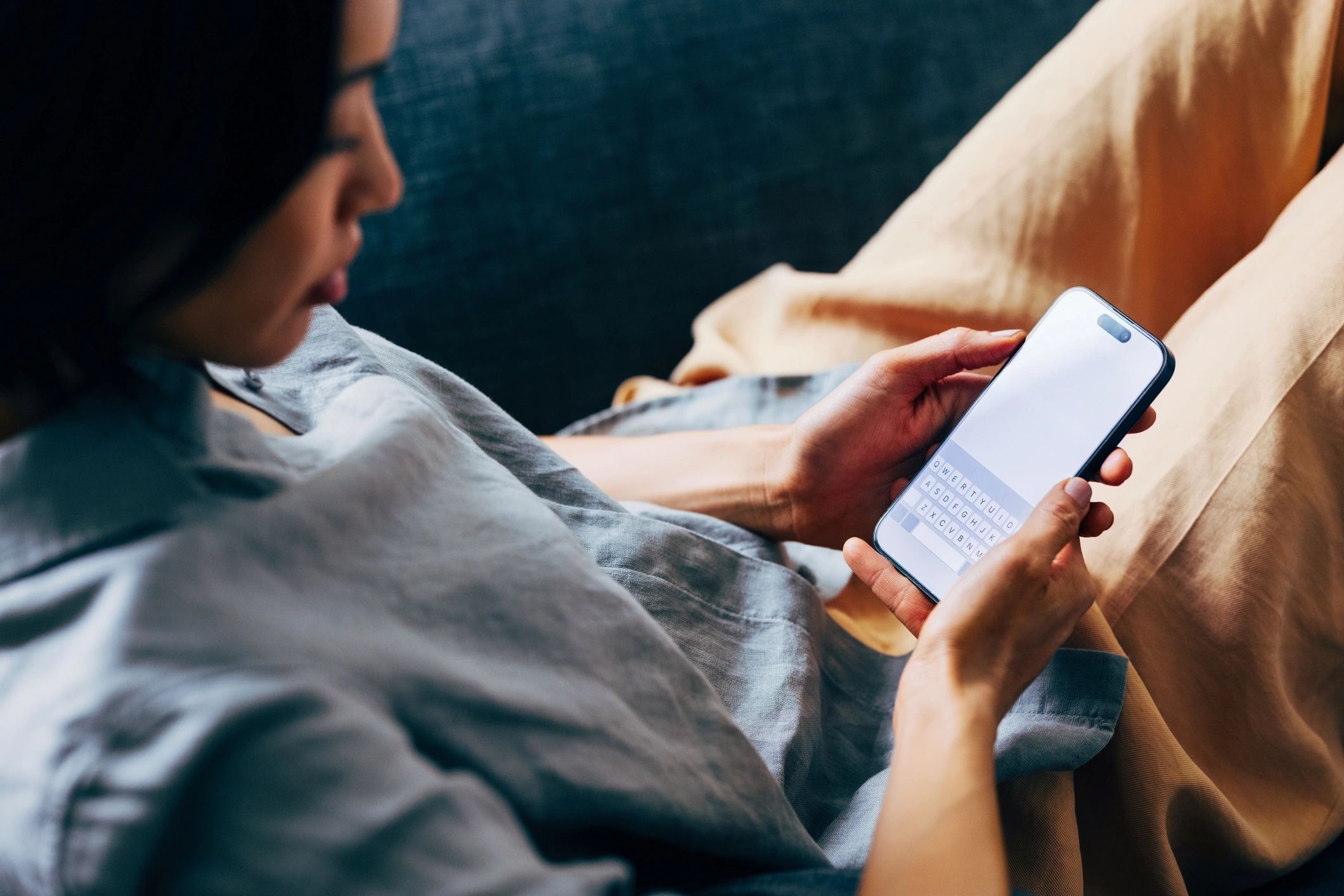 Personne utilisant un smartphone pour communiquer depuis un canapé